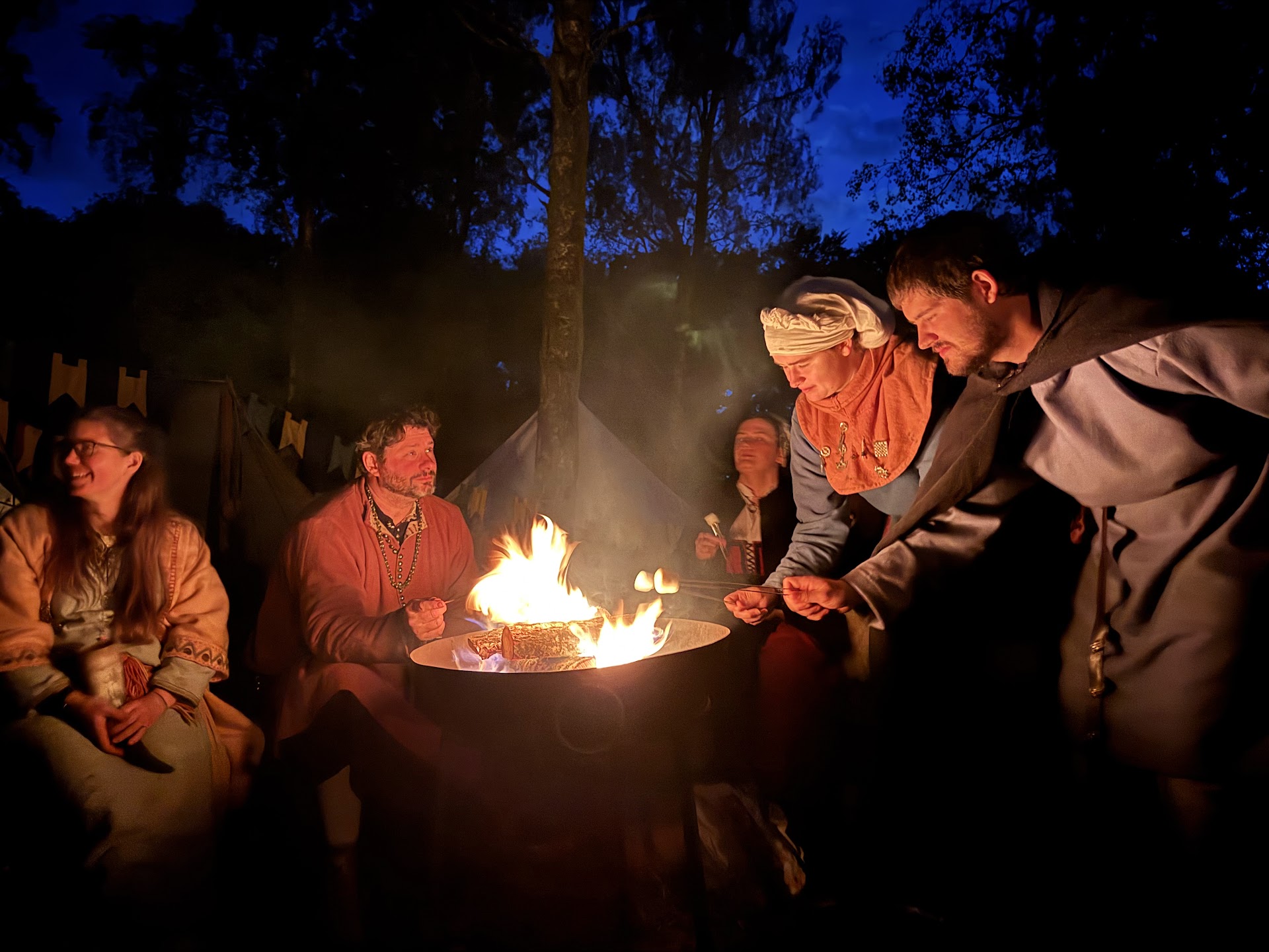 Freunde lachen unter freiem Himmel und rösten gemeinsam Marshmallows am Lagerfeuer
